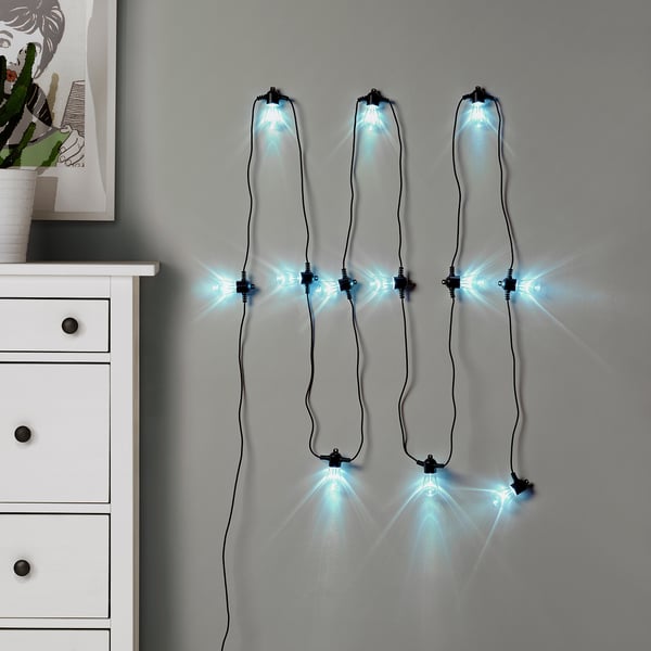 Guirlandes lumineuses bleues KASTTÅG sur le mur au-dessus du tiroir blanc.