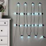 Chaînes lumineuses suspendues au mur, lueur bleue, ambiance chaleureuse, commode partiellement visible