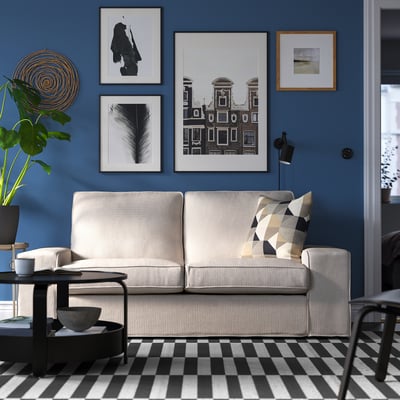 Salon moderne avec canapé KIVIK, tapis à carreaux, murs bleus et art mural.