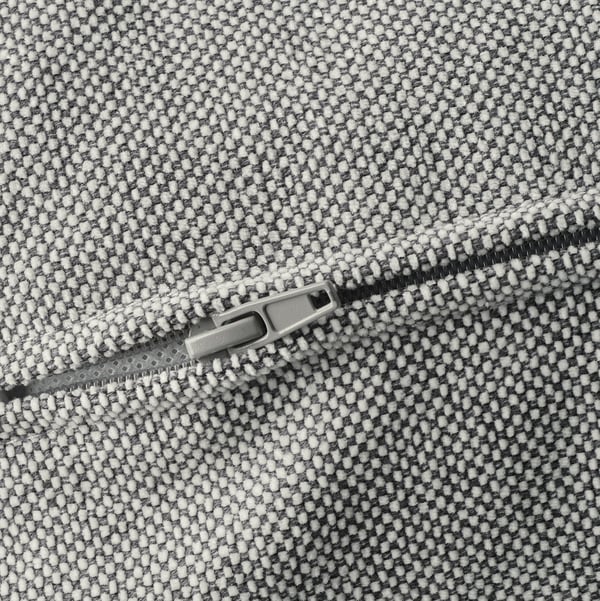 Détail de la fermeture éclair d’un tissu semblable à du tweed, peut-être d’un canapé ou d’un sac, montré en gros plan.