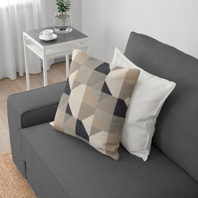 Canapé gris avec coussins géométriques, design confortable, table d’appoint près de blanc.