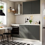 Ensemble de cuisine gris foncé KNOXHULT avec comptoir en marbre, design minimaliste sous suspension noire.