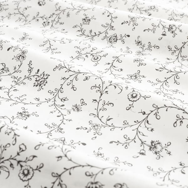 Drap de lit à motifs floraux, finement détaillé, doux, dans les tons noirs et blancs, avec de petites fleurs et des vignes, offrant un look romantique et rêveur.