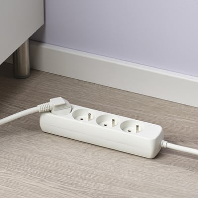 Rallonge blanche avec 3 prises sur parquet, offrant des prises supplémentaires.