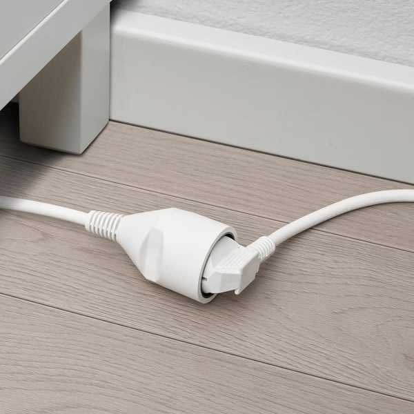Cordon d’alimentation blanc avec prise plate sur plancher en bois.