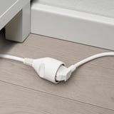 Cordon d’alimentation blanc avec prise plate sur plancher en bois.