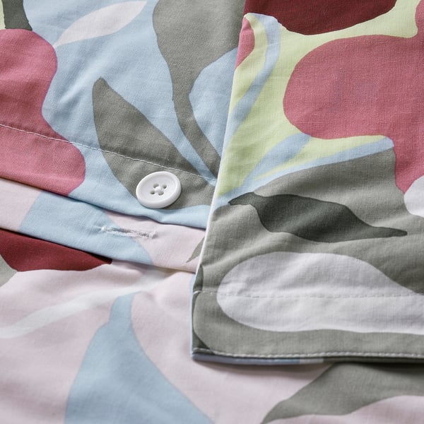 Gros plan d’une housse de couette multicolore à motifs floraux avec un bouton blanc et une fermeture enveloppe.