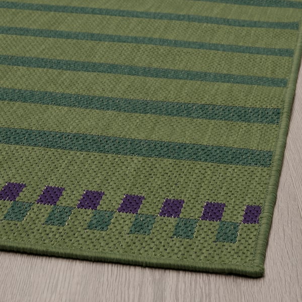 Tapis à rayures vertes avec des motifs de losanges violets ; Conception durable à tissage plat.