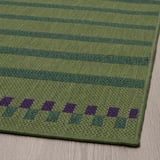 Tapis à rayures vertes avec des motifs de losanges violets ; Conception durable à tissage plat.
