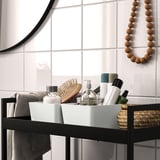 Comptoir de salle de bain moderne avec étagère noire, serviettes, panier et décoration murale