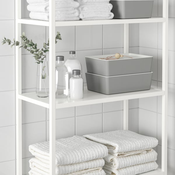 Étagère blanche avec serviettes blanches soigneusement empilées et bacs de rangement, y compris une boîte KUGGIS grise pour organiser les articles de salle de bain ou de bureau.