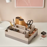 Organisateur de bureau contenant des ciseaux, des stylos, une calculatrice et du papier. Plusieurs compartiments et une poignée pour le transport.