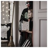 Jeune garçon en costume d’Halloween tenant une boîte emballée dans un emballage cadeau, peut-être pour la chasse aux bonbons.