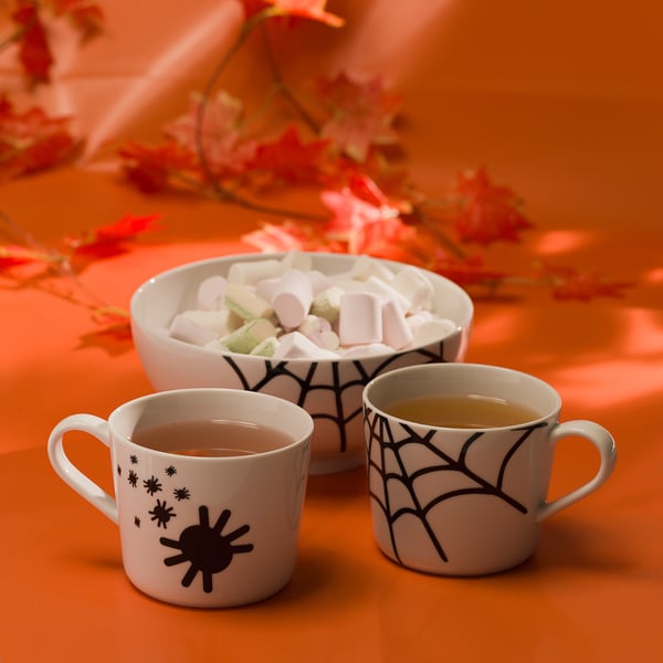 Tasses d’Halloween et bol de guimauve avec des fleurs.