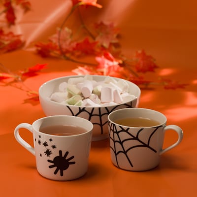 Tasses d’Halloween et bol de guimauve avec des fleurs.