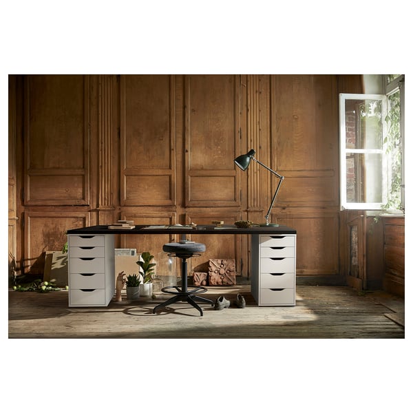 Configuration du bureau à domicile : bureau LAGKAPTEN blanc avec tiroirs, chaise, lampe et plantes contre un mur lambrissé en bois.