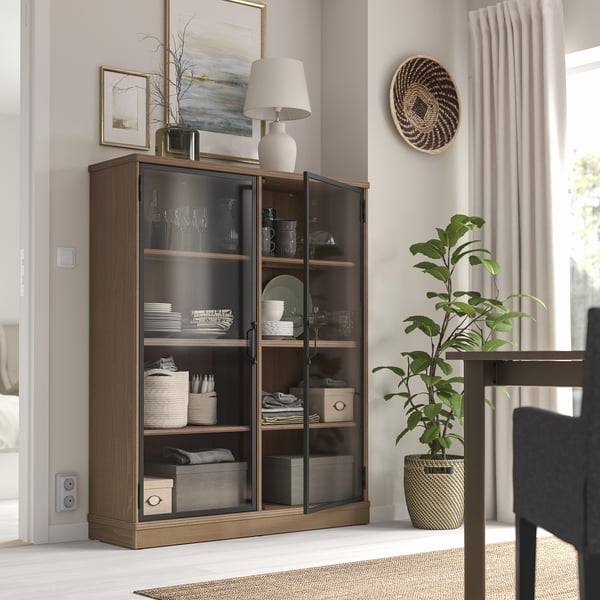Armoire LANESUND avec portes vitrées, lampe et décoration dans une pièce spacieuse
