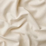Rideaux doux et blanc cassé avec œillets, confectionnés en 100 % coton lisse, affichant un tissage linéaire et des plis doux.