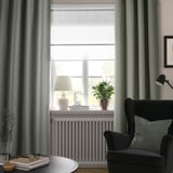 Chambre confortable avec rideaux gris-vert LENDA, chaise noire, plante, lampe et vase.