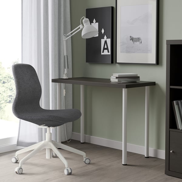 Bureau LINNMON gris foncé à côté de la fenêtre, avec chaise et livres.