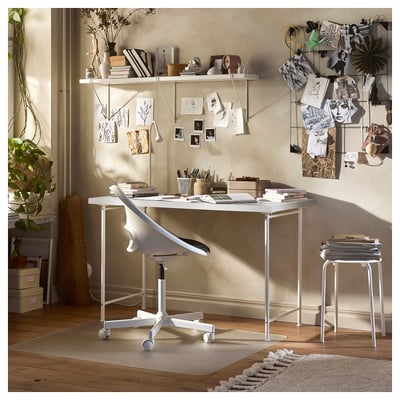 Espace de travail lumineux et moderne doté d’une table lindom blanche avec chaise réglable, entourée de livres, d’œuvres d’art et d’objets décoratifs.