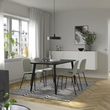 Salle à manger moderne avec ensemble 4 places LISABO, table noire, chaises grises, tapis rayé et œuvres d’art.