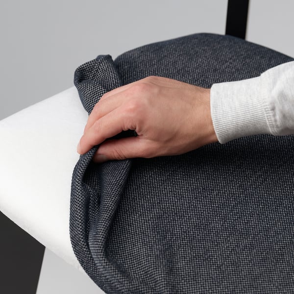 Personne ajustant la housse de chaise douce et amovible sur une table blanche moderne.