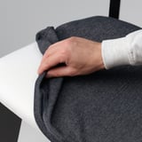 Personne ajustant la housse de chaise douce et amovible sur une table blanche moderne.