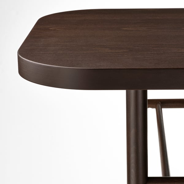 Gros plan d’une table en bois foncé avec des bords élégants et incurvés et des pieds en métal robustes, illustrant un savoir-faire de haute qualité et un design durable.