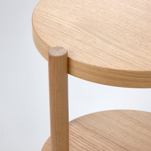 Table d’appoint moderne en bois avec plateau lisse et circulaire et pied central robuste. Finition chêne naturel clair.