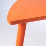 Une table d’appoint élégante et orange avec un plateau lisse et plaqué et des pieds effilés robustes. Fait partie de la collection nytillverkad, présentant un design moderne.