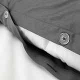 Gros plan d’une housse de couette grise avec bouton et tissu lisse, montrant des coutures fines et un tissage satiné brillant.