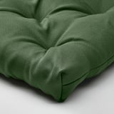 Coussin de chaise vert, épais et rembourré, en matériau recyclé, se plie soigneusement.