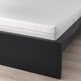 Cadre de lit noir avec matelas blanc, montrant des lattes de soutien et un espace spacieux sous le lit.