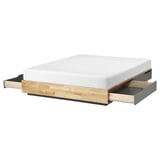 Un lit en bois nommé MANDAL avec des tiroirs en finition bois clair. Il est moderne et fonctionnel, avec quatre grands tiroirs de rangement en dessous.