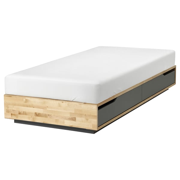 Un lit MANDAL en bois clair et noir. Il a des tiroirs intégrés et un design minimaliste.