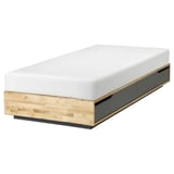 Un lit MANDAL en bois clair et noir. Il a des tiroirs intégrés et un design minimaliste.