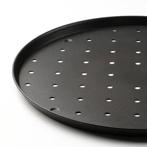 Gros plan d’une plaque à pizza antiadhésive avec des trous régulièrement espacés pour la circulation de l’air.