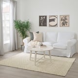 Salon moderne avec tapis MARSTRUP blanc, table basse, canapé et plantes.