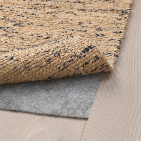 Tapis en jute tissé à la main avec des accents de laine, surface texturée, dessous en feutre antidérapant.