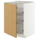 Une armoire METOD blanche avec une porte en bois s’ouvre, révélant des étagères en fil de chrome à l’intérieur.