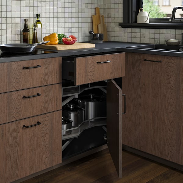 Armoire d’angle de cuisine en bois avec étagères coulissantes pour les grandes casseroles, dotée de charnières réglables et d’une finition foncée.