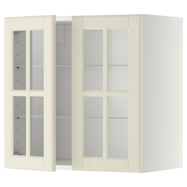 Une armoire murale METOD de couleur crème avec des portes en verre. Il a une forme rectangulaire et un design traditionnel, avec des étagères réglables.