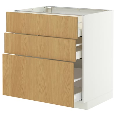 Armoire de cuisine en bois avec trois tiroirs en chêne clair. Bords blancs élégants, cadre robuste, tiroirs à fermeture automatique.