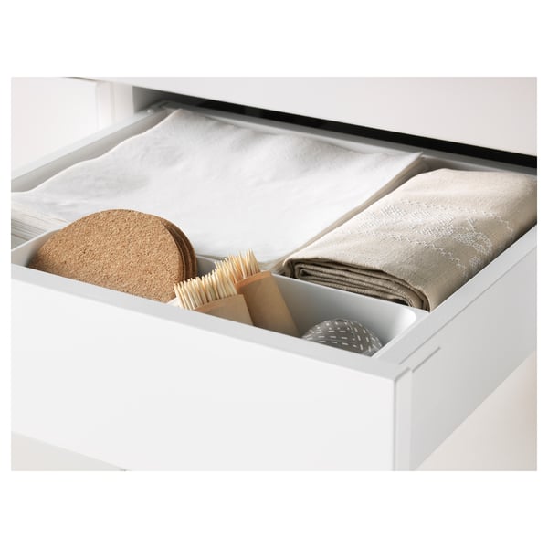 Tiroir de cuisine ouvert montrant des serviettes pliées et des outils de nettoyage, démontrant le rangement et l’organisation.