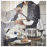 Servir des aliments fumants d’une casserole MIDDAGSMAT dans un bol. A proximité, du pain et un verre.