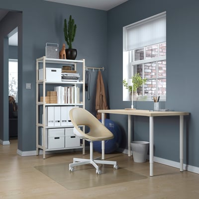 Configuration du bureau à domicile : bureau en bois clair MITTCIRKEL contre mur bleu foncé avec chaise blanche et tabouret roulant.