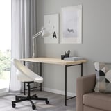 Bureau à domicile minimaliste avec bureau en bois clair MITTCIRKEL, chaise blanche et décor géométrique. Le bureau est plus petit que le fauteuil, avec des pieds en métal élégants.