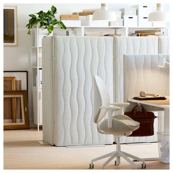 L’écran acoustique MITTZON à texture blanche divise l’espace de travail moderne avec un bureau, une chaise, un sac et une plante.