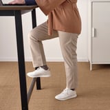 Dans une personne est debout et travaille à une table haute avec un repose-pieds, parfaite pour des réunions rapides ou des tâches en position debout.